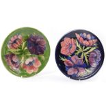 A pair of Moorcroft pottery plates, decorated in the Anemone pattern, one against a blue ground, the