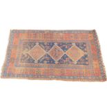 A Qashqai rug, decorated with three geometric motifs within borders of further motifs and flowers,