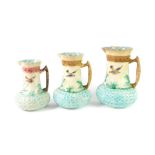 A set of three Continental late 19thC majolica graduated jugs, moulded with birds and leaves,