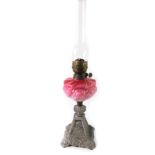 A Victorian silver painted cast iron oil lamp, with a pink to ruby opaline glass reservoir, with