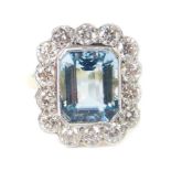 An 18ct gold aquamarine and diamond ring, the rectangular cut aquamarine in a surround of 14