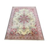 A Wilton Ambala rug, decorated with floral motifs against a cream and red ground within a white