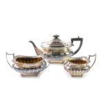A George V silver semi fluted three piece tea set, the rims with gadrooned and embossed shell