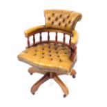 A Victorian style mahogany and yellow leather captain's chair, with button back headrest and over