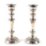 A pair of loaded silver candlesticks, of baluster form, with embossed foliate scroll decoration,