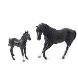 A Beswick matt black figure of a swish tail horse, front left leg partly raised, head to the left,