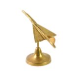 A brass desk stand modelled as Concorde, raised on a circular base, 17cm W.
