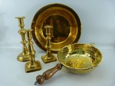 Antique brassware to include a brass and copper sive with turned wooden handle, three candlesticks