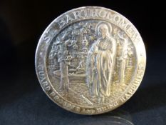 White metal pin cushion, of circular form, the top embossed with St. Bartholomew in a garden setting
