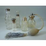 Five cut glass bottles four with hallmarked silver lids or collars, the scent bottle is silver
