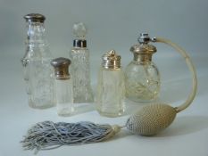 Five cut glass bottles four with hallmarked silver lids or collars, the scent bottle is silver