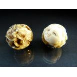 Two Japanese ivory nestuke beads - 1 depicting mens faces and the other carved with dragon set