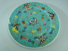 Oriental enamelled plate with turquoise ground depicting butterflies and flowers.