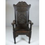 Wainscott Oak antique chair with heavily carved back and arms on block feet.