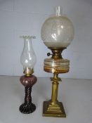 Antique brass based oil lamp with clear glass well and one other in an unusual Amethyst colour.