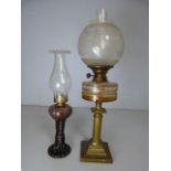 Antique brass based oil lamp with clear glass well and one other in an unusual Amethyst colour.