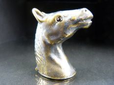 Brass cased vesta in the form of a horse head with red eyes.
