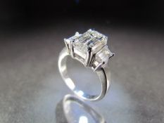 White Gold three stone Diamond ring. The Emerald Cut centre stone is approx 4ct, measuring approx