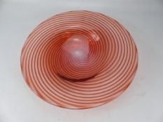 Art glass charger decorated with red swirls through clear glass.