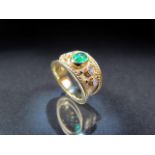 18CT yellow gold Cartier-style wide banded ring with central emerald flanked by diamonds