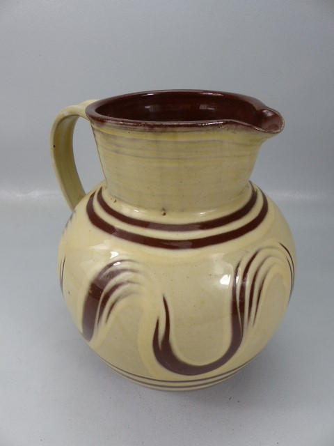 Large bulbous slipware glaze jug in cream and earthenware red. Marked to base L'Etacq, Jersey JW.