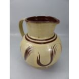 Large bulbous slipware glaze jug in cream and earthenware red. Marked to base L'Etacq, Jersey JW.