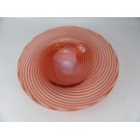 Art glass charger decorated with red swirls through clear glass.