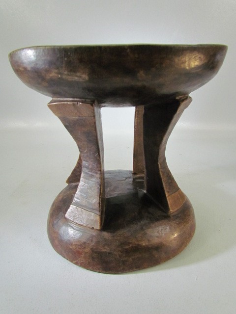 Hand carved tribal/African headrest on base with four supports and green hue to the upper surface