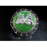 Designer brooch in silver with filigree work ring and set with a large flat green stone, mounted