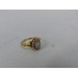 18ct Gold ladies ring set with pale blue stone (rubbed) surrounded by small diamond chips