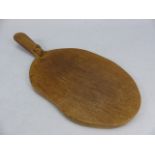 A Robert Mouseman Thompson of Kilburn carved oak cheese/ bread board, oval form with carved mouse to