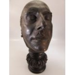 Bronze death mask on carved wooden plinth. Overall height approx 37cm