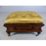 Rosewood footstool with single drawer and upholstered gold cushion on brass castors