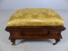 Rosewood footstool with single drawer and upholstered gold cushion on brass castors