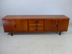 Mid century sideboard with two cupboards with retractable doors and three central drawers. Marked