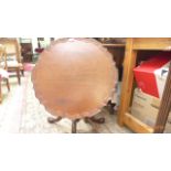 Circular tilt topped mahogany side table on tricorn base on ball and claw feet