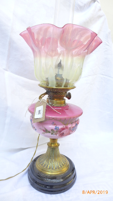 A converted Victorian oil lamp on fluted brass base on circular ebonised plinth,