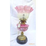 A converted Victorian oil lamp on fluted brass base on circular ebonised plinth,