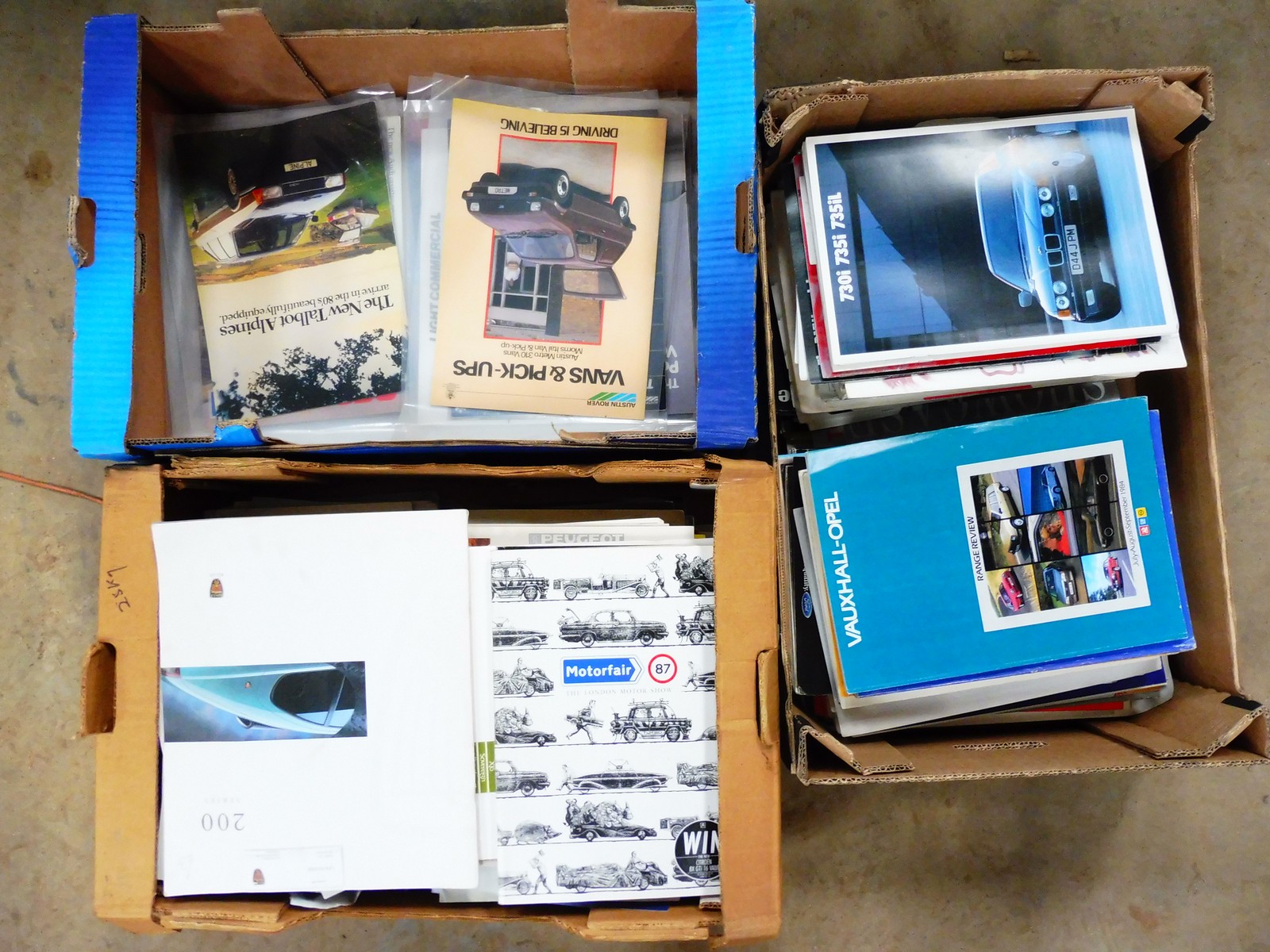 Three boxes of assorted car brochures.