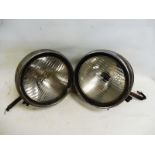 A pair of large chrome plated headlamps with ribbed lenses, requiring restoration.