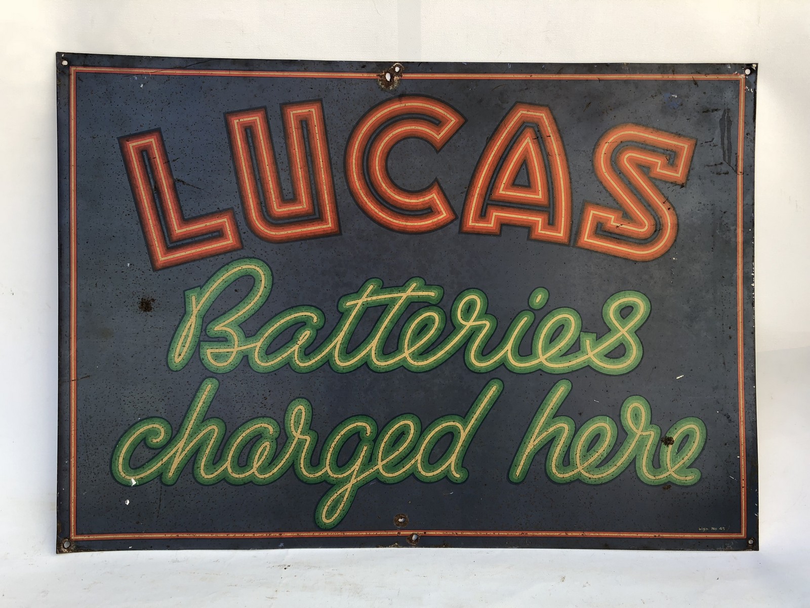 A 'Lucas Batteries Charged Here' rectangular tin advertising sign, 27 x 19".