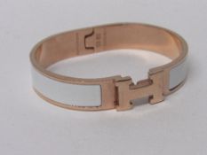 A gold coloured & white Hermes bracelet. Estimate £100-120.