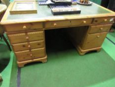 Pine pedestal desk with green leather skiver, on castors, 154cms x 76cms x 76cms. Estimate £50-70.