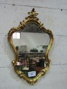 Ornate gilt shaped wall mirror. Estimate £30-50.