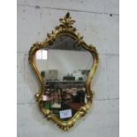 Ornate gilt shaped wall mirror. Estimate £30-50.