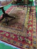 Red ground wool carpet, 280cms x 190cms. Estimate £50-80.