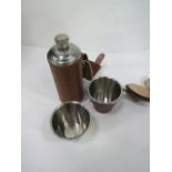 Small flask in a leather holder & 4 cups in leather container. Estimate £15-25.