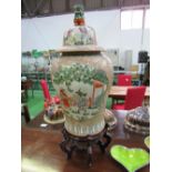 A large Chinese lidded jar decorated with family scenes, the lid with Dog of Fo, on wooden stand,