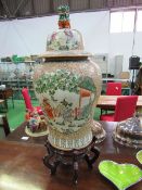 A large Chinese lidded jar decorated with family scenes, the lid with Dog of Fo, on wooden stand,