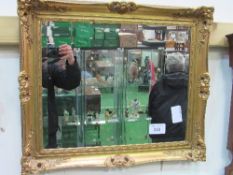 Gilt framed ornately decorated bevel-edged wall mirror. Estimate £20-40.